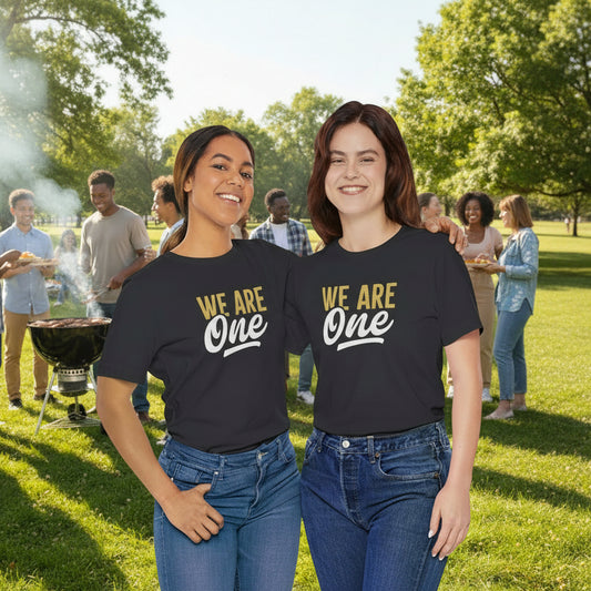 Two women wearing black t-shirts with 'WE ARE One' text on a white background